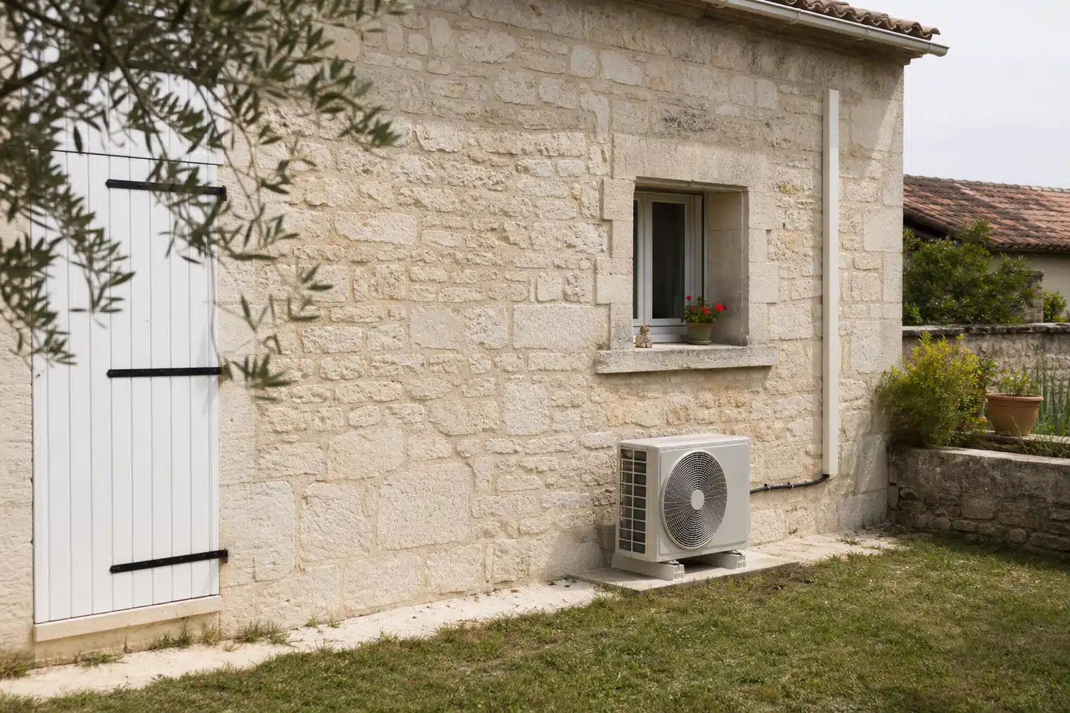 Climatiseur extérieur posé contre mur en pierre